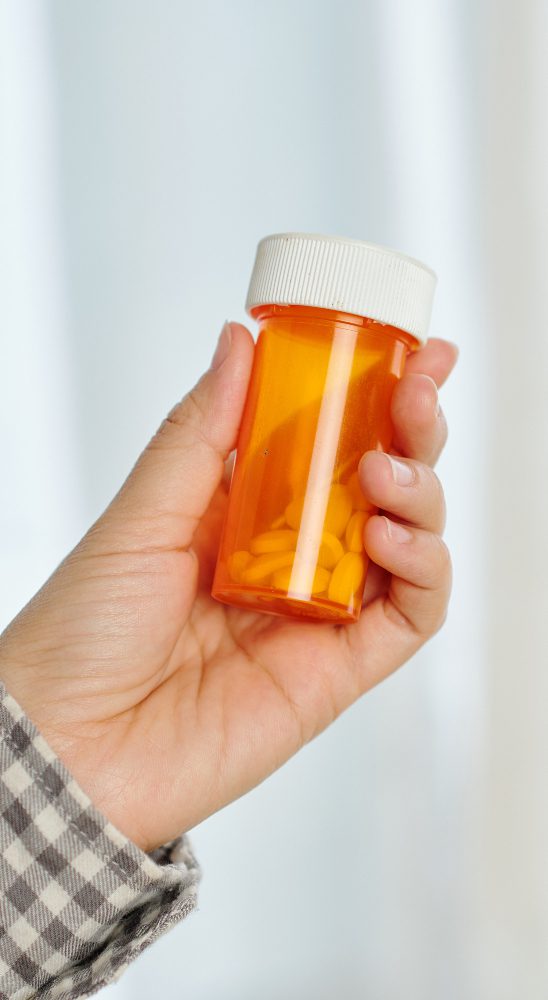 close up of man holding pill bottle full of opioids